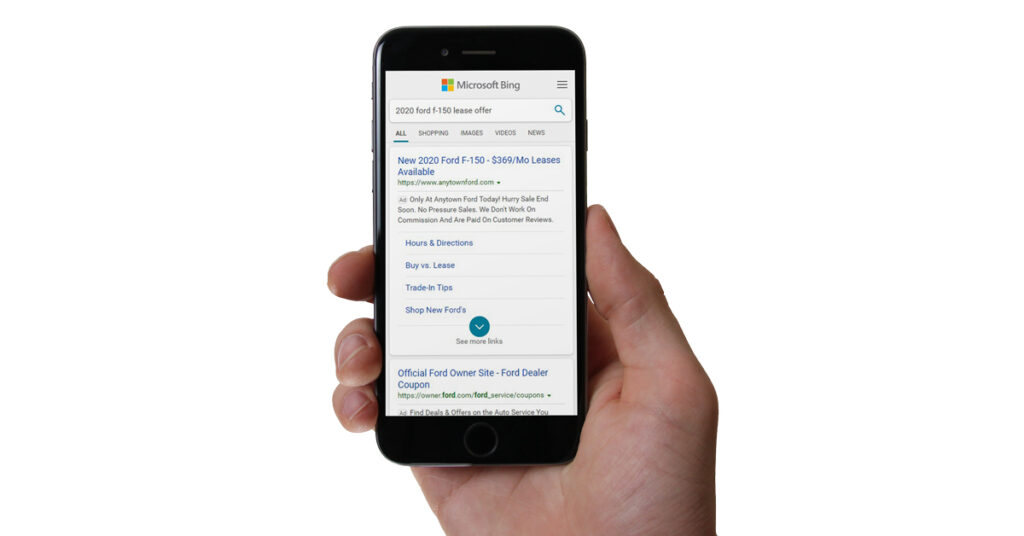person holding mobile phone looking at a paid search ad on bing